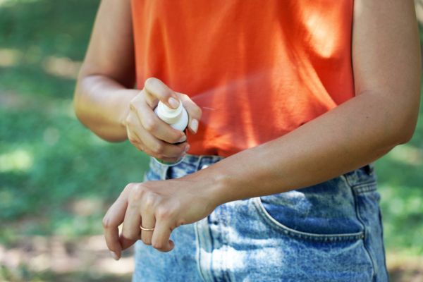 Person spraying bug spray on arm