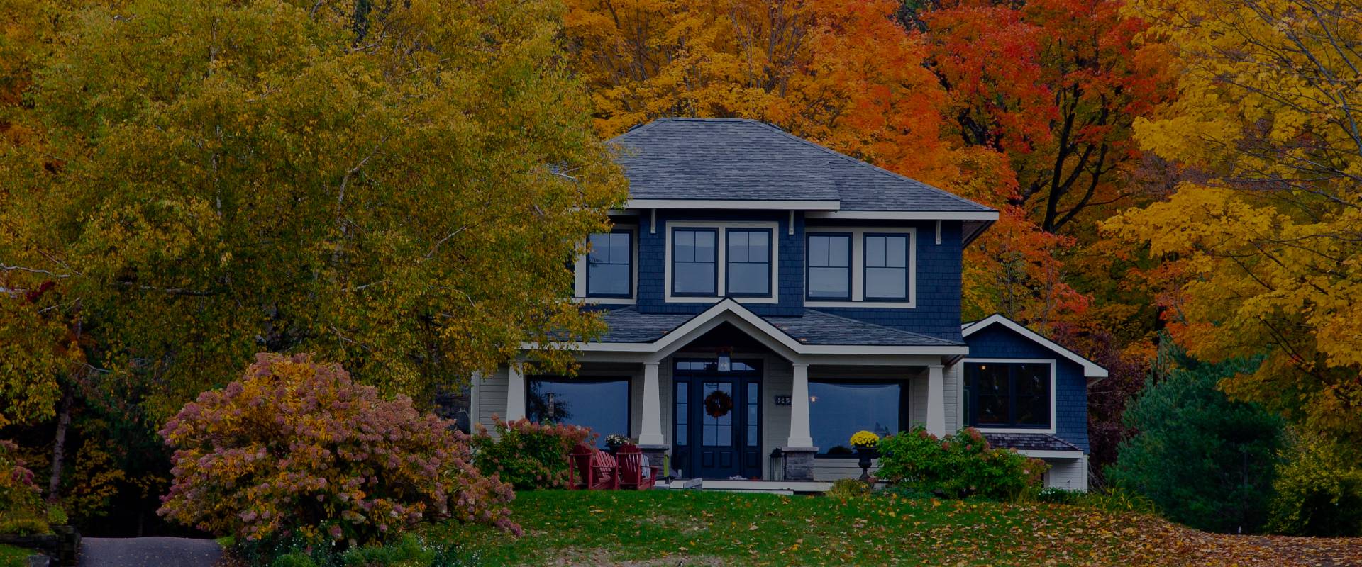 House in front of trees with brown and orange leaves