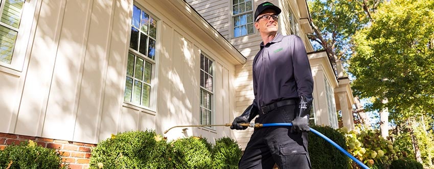Terminix technician spraying outside a home